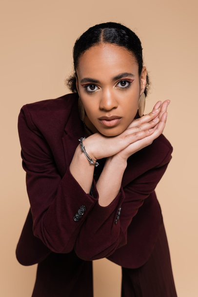 young african american woman in stylish maroon blazer posing isolated on beige  - Foto, afbeelding