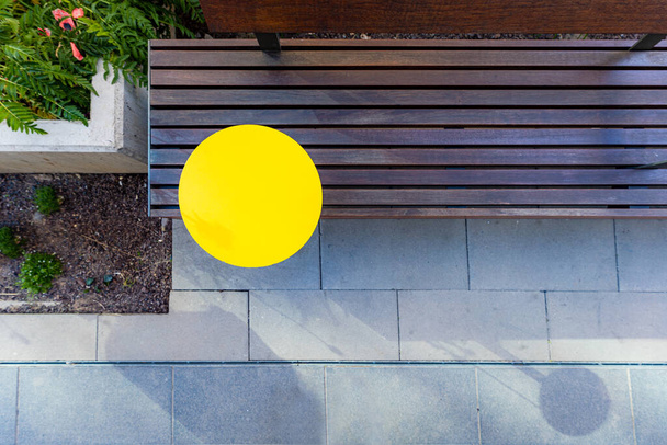Draufsicht auf eine Holzbank mit einem runden gelben Tisch im Garten - Foto, Bild