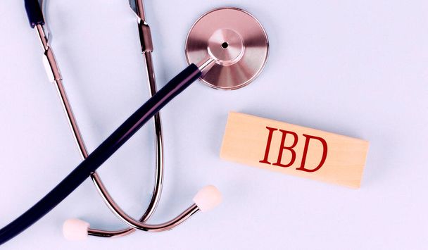 Sinisellä pohjalla stetoskooppi ja puinen lohko sanalla IBD. Lääketieteellinen käsite - Valokuva, kuva