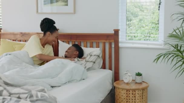 Afrikanisches Paar küsst sich im Bett und entspannt sich glücklich zusammen im Hotelzimmer unter Decken. Junge Eheleute lächeln, pflegen und glücklich sein, während sie sich im Urlaub oder auf Flitterwochen liebevoll küssen. - Filmmaterial, Video