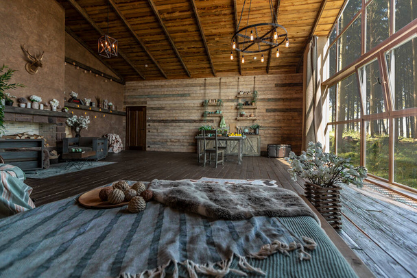 dark cozy interior of big country wooden house, wooden furniture and animal furs. huge panoramic window and very high ceiling. - Fotografie, Obrázek