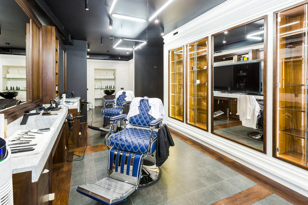 luxury barber shop interior, blue expensive furniture, wood trim, fashionable black ceiling, white robes on the backs of armchairs - Foto, Imagem