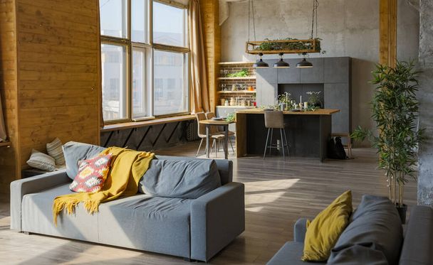 Dark loft style interior of big cozy country house. open plan apartment with kitchen area, rest zone and bed area. Huge windows and wooden decoration - Foto, Imagen