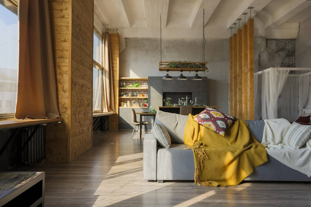 Dark loft style interior of big cozy country house. open plan apartment with kitchen area, rest zone and bed area. Huge windows and wooden decoration - Foto, afbeelding