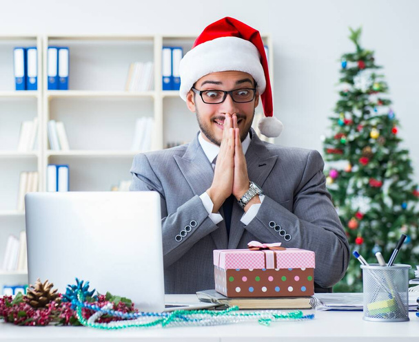 A fiatal üzletember ünnepli a karácsonyt az irodában. - Fotó, kép