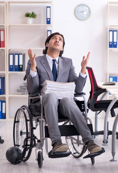 El joven empleado guapo en silla de ruedas que trabaja en la oficina - Foto, imagen