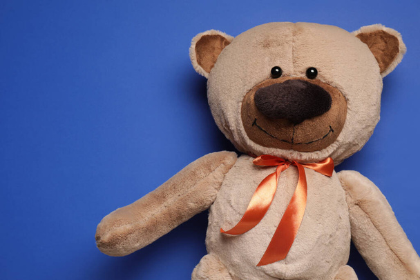 Cute teddy bear on blue background, top view. Space for text - 写真・画像