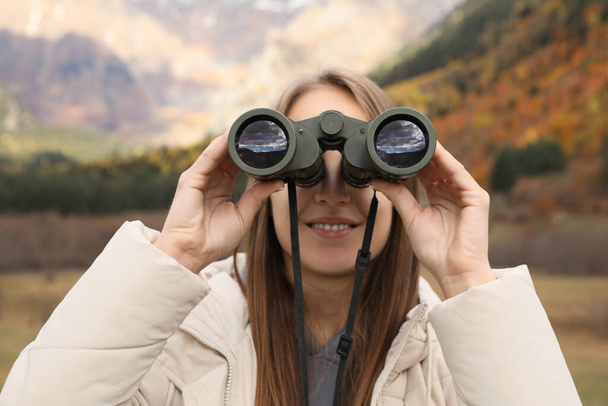 Woman looking through binoculars in beautiful mountains, closeup - Foto, imagen