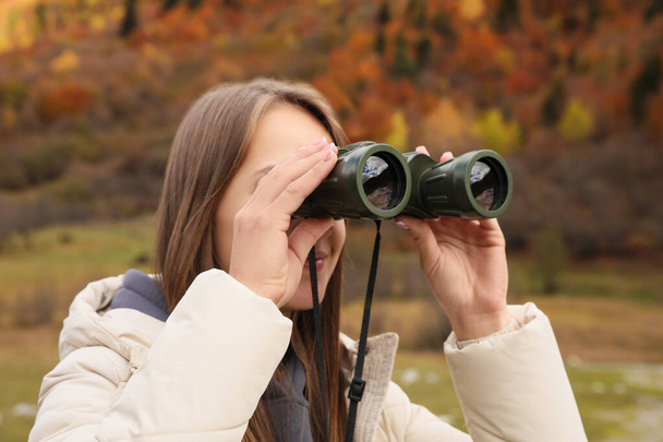 Woman looking through binoculars in beautiful mountains, closeup - Foto, Imagen
