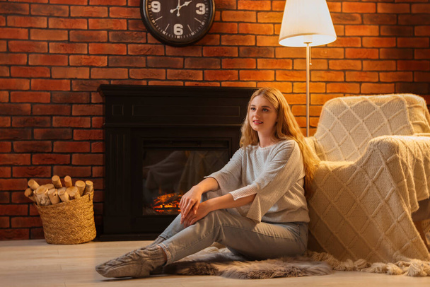 Beautiful young woman resting near fireplace at home - Foto, immagini