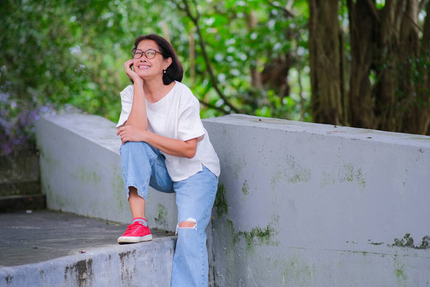 Asian woman sitting alone and taking a rest after a long walk in the park - Photo, Image