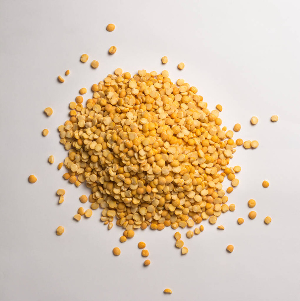 heap of yellow split peas, dried, peeled and split seeds of pea, isolated on neutral gray background, taken from above - Photo, Image