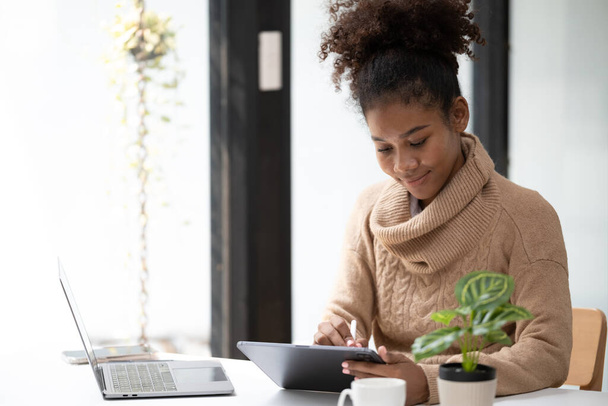 Amerikanische Afroamerikanerin arbeitet im Büro mit Computertelefon und Tablet. Hochwertiges Foto - Foto, Bild