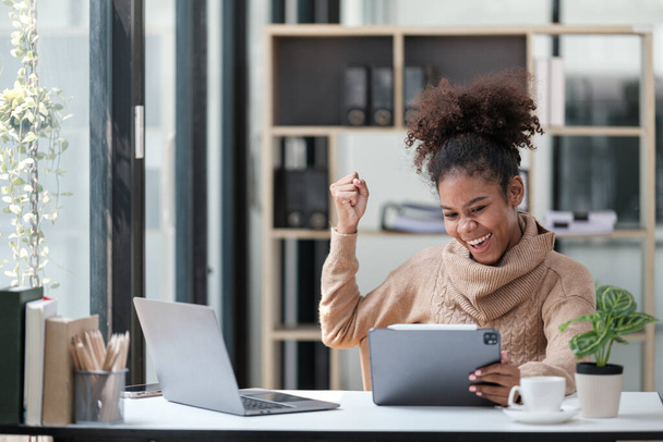 Американская афроамериканка работает в офисе с компьютерным телефоном и планшетом. Высокое качество фото - Фото, изображение