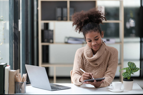 Amerikai afrikai nő dolgozik az irodában számítógépes telefonnal és tablettel. Kiváló minőségű fénykép - Fotó, kép