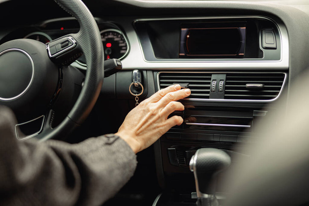 Naiskäsi ohjaa auton ilmastointijärjestelmän ruudukkopaneelia konsolilla. Laadukas kuva - Valokuva, kuva