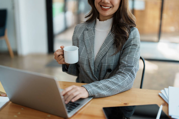 コンピュータで話をしてコーヒーを飲むビジネス女性の肖像画. - 写真・画像