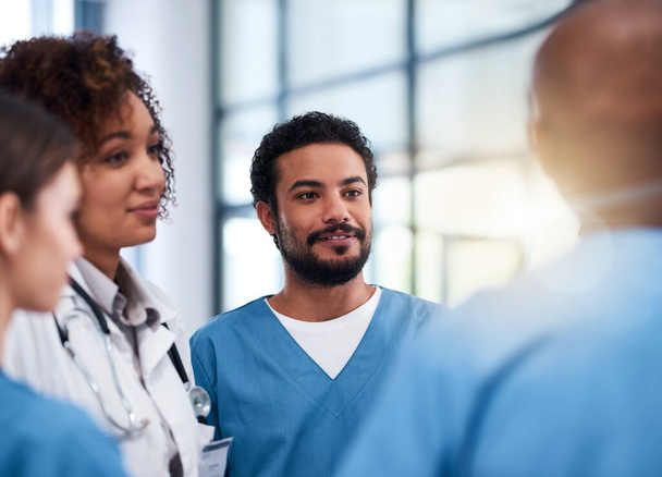 Le personnel médical se moque. un groupe joyeux de médecins qui discutent pendant qu'ils se tiennent à l'intérieur d'un hôpital pendant la journée - Photo, image