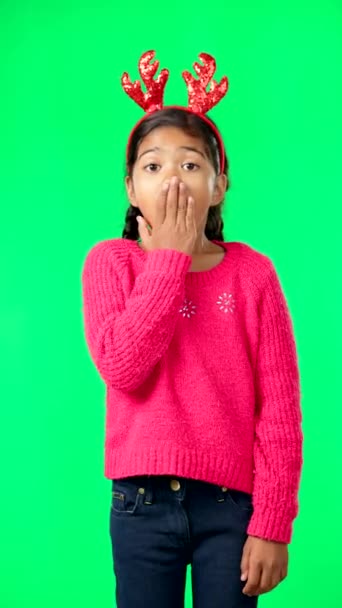 Child, christmas and shocked on green screen for secret or sale studio background. Face of girl kid with antlers headband and hand on mouth for holiday celebration announcement, surprise or portrait. - Filmmaterial, Video