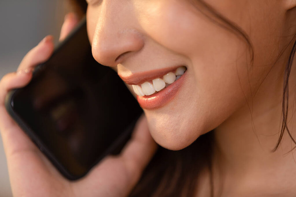 Close up of beautiful woman mouth and teeth talking on mobile phone happiness with positive emotional. Beautiful lips smile nice and gentle. - Valokuva, kuva