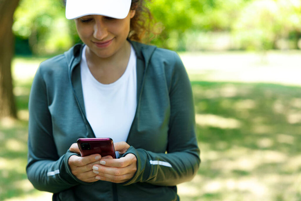 Young athlete woman using mobile phone after outdoor running workout - Foto, Imagen