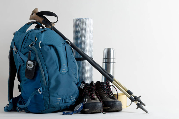 Close up of backpack, trekking shoes, thermos and mat on white background with copy space. National camping month, equipment and celebration concept. - Fotografie, Obrázek
