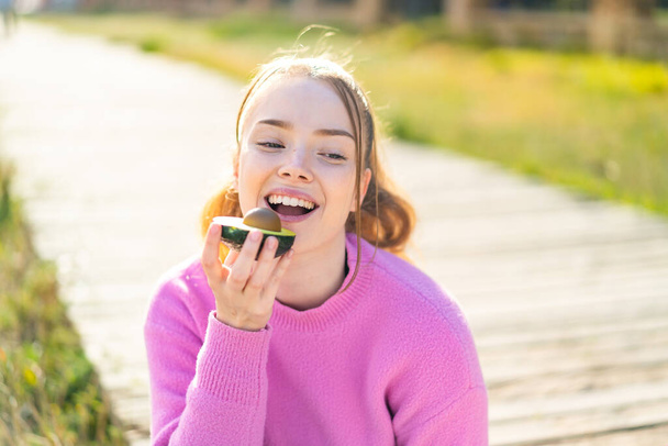Junges hübsches Mädchen im Freien mit einer Avocado - Foto, Bild