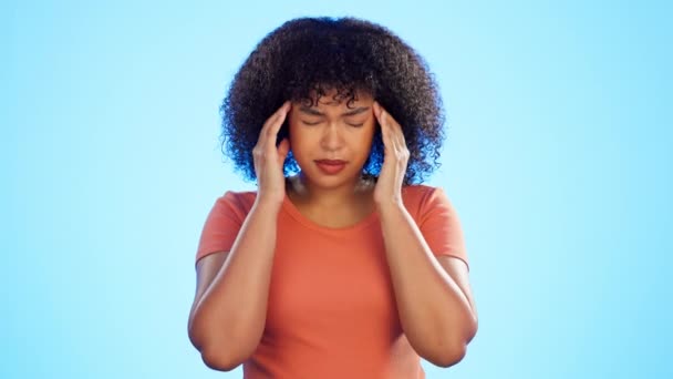 Woman, headache and face of pain in studio with stress, brain fog and mental health. Sick female model massage temple of migraine, fatigue and anxiety of burnout, trauma psychology or blue background. - Footage, Video