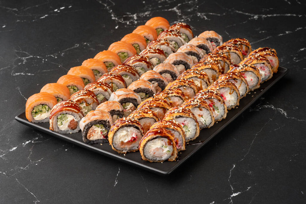 Japanese rolls with fish, vegetables and cottage cheese. Big set of sushi rolls and nigiri with tuna, salmon, shrimp, avocado, cream cheese, red flying fish caviar, seaweed and sesame. - Fotoğraf, Görsel