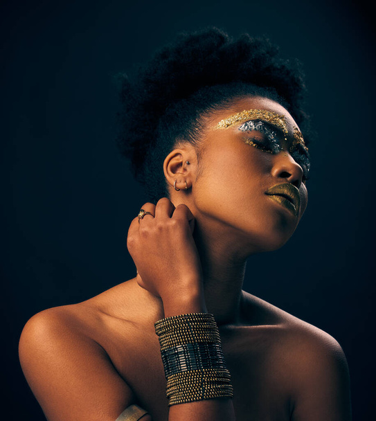Beauty, gold and jewelry with black woman and makeup in studio for luxury, cosmetics and African pride. Natural, creative and goddess with female model on background for queen, bronze and glamour. - Photo, Image