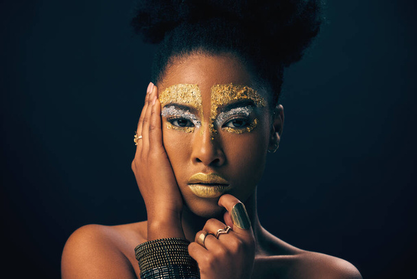 Μακιγιάζ, χρυσό και φαντασία με πορτρέτο της μαύρης γυναίκας στο στούντιο για πολυτέλεια, καλλυντικά ή αφρικανική υπερηφάνεια. Φυσική, δημιουργική και θεά με γυναικείο μοντέλο στο φόντο για τη βασίλισσα, χάλκινο ή αίγλη τέχνη. - Φωτογραφία, εικόνα