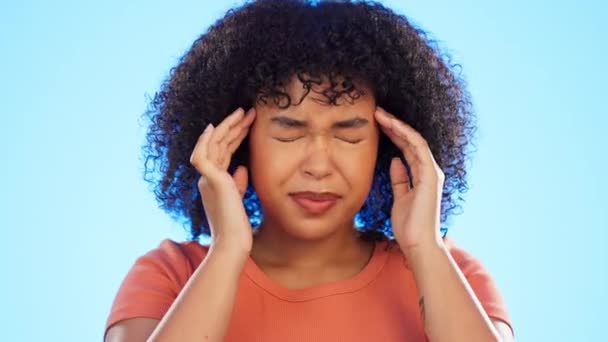 Black woman, headache and pain with face and stress, burnout with health and crisis on blue background. Female hands, migraine in studio and agony, medical problem with mental health and anxiety. - Footage, Video
