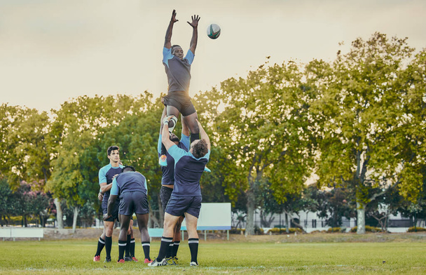 Sport, men and rugby and jump with team on field, playing game with energy and fitness, ball and action outdoor. Training, exercise and professional match, sports club with male group and active. - Photo, Image