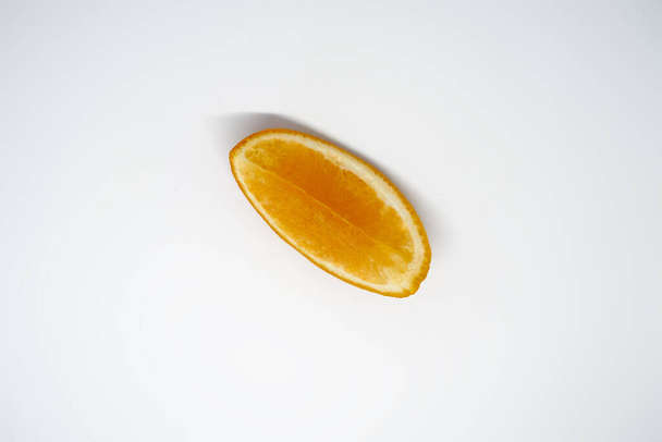 Eine Orangenscheibe auf weißem isoliertem Studiohintergrund - Foto, Bild