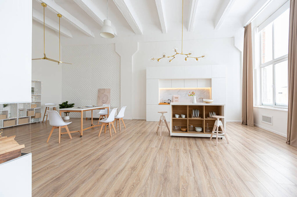 interior design spacious bright studio apartment in Scandinavian style and warm pastel white and beige colors. trendy furniture in the living area and modern details in the kitchen area. - Φωτογραφία, εικόνα