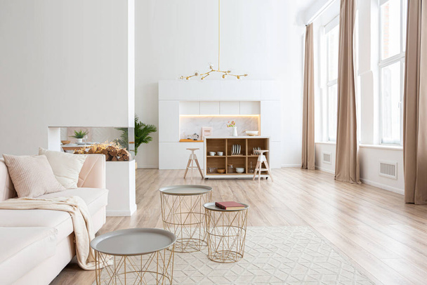 interior design spacious bright studio apartment in Scandinavian style and warm pastel white and beige colors. trendy furniture in the living area and modern details in the kitchen area. - Zdjęcie, obraz