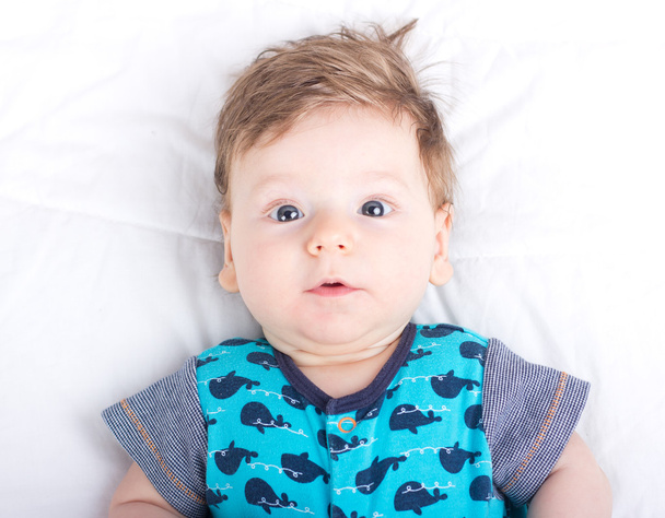 Portrait d'un enfant souriant. Un enfant sur un lit blanc. Beau garçon
. - Photo, image