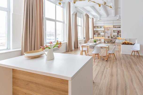 interior design spacious bright studio apartment in Scandinavian style and warm pastel white and beige colors. trendy furniture in the living area and modern details in the kitchen area. - Foto, imagen
