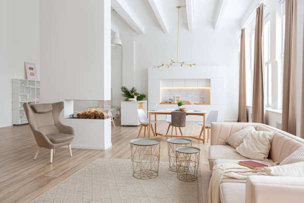 interior design spacious bright studio apartment in Scandinavian style and warm pastel white and beige colors. trendy furniture in the living area and modern details in the kitchen area. - Fotoğraf, Görsel