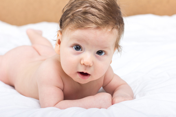 Portrait of a naked child. A child on a white bed. Handsome boy. smiling child - Фото, изображение
