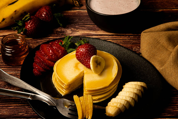 Délicieuse assiette de crêpes accompagnée de bananes et de fraises avec une couche de miel - Photo, image