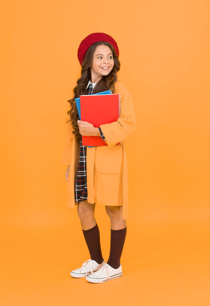 in good mood. kid in french beret on yellow background. stylish teen college student. little girl with notebook or workbook for lesson. education concept. school and fashion. child in pupil uniform. - Foto, afbeelding
