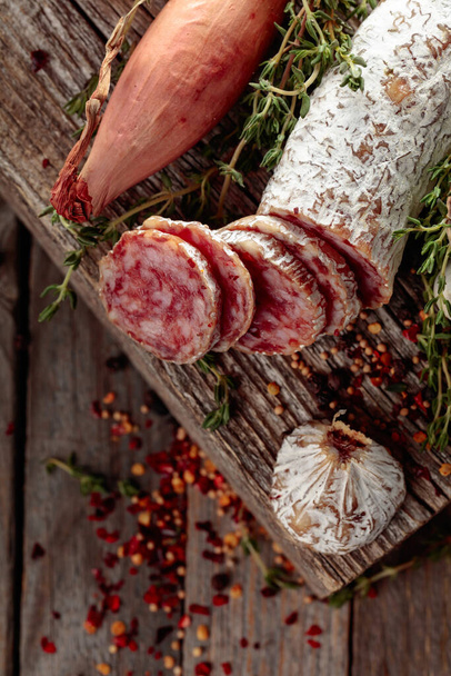 Traditional dry-cured sausage with thyme, garlic, onion, and spices. Dry-cured sausage on a old wooden table. - Foto, Imagem