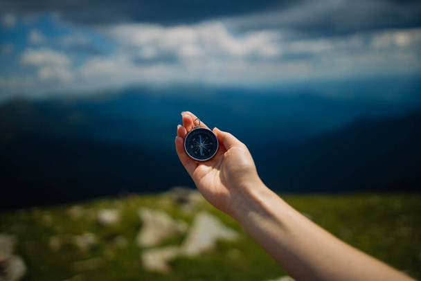Traveler with compass seeking a right way in the mountains during hike. Navigation concept in explore travel. - Photo, Image