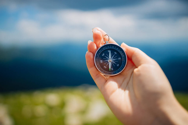 Traveler with compass seeking a right way in the mountains during hike. Navigation concept in explore travel. - Foto, Bild