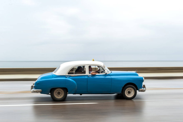 HAVANA, CUBA - 21 Ekim 2017: Havana, Küba 'daki eski araba. Pannnig. Retro Araç genellikle yerel halk ve turistler için bir taksi olarak kullanılır. Arka planda Karayip Denizi. Mavi Renk - Fotoğraf, Görsel