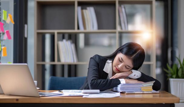Empresária asiática é séria no trabalho causando dor de cabeça estressada com documentos com um laptop no escritório... - Foto, Imagem