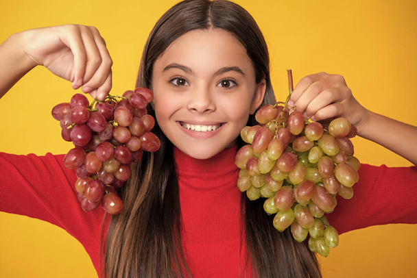 girl smile hold bunch of grapes on yellow background. - Фото, изображение