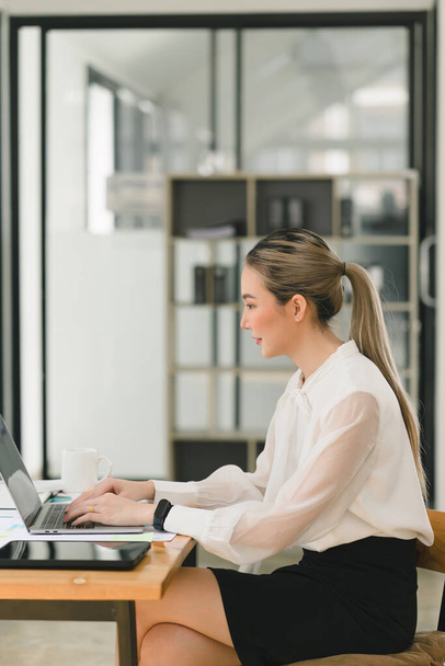 Technikaffin und geschäftstüchtig: Eine junge, attraktive Geschäftsfrau gedeiht mit ihrem vertrauenswürdigen Laptop im modernen Büro - Foto, Bild