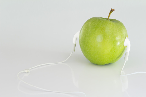 Fechar a maçã verde conceitual com fone de ouvido
 - Foto, Imagem